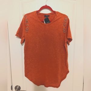 Orange shirt with silver accessories.